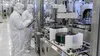 Cleanroom technicians monitor semiconductor wafer-processing equipment.