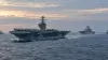 Illustrative view of a modern aircraft carrier and escort ships underway at dawn