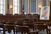 An empty Mississippi legislative hearing room with an abstract state map prepared for redistricting discussion.
