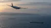 A maritime patrol aircraft and surveillance drone fly above commercial ships on the Black Sea.