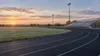 Illustrative view of an empty Nebraska school running track and bleachers at sunrise.