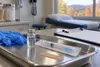 A generic vaccine vial and sealed syringe on a medical tray in a rural clinic.