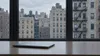 AI-generated editorial image of a generic New York apartment facade viewed from an unbranded office desk.