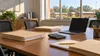 Illustrative view of a school administration meeting table with budget folders and school buses beyond a window.