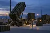 Illustrative AI-generated image of a Patriot-style air-defense battery under maintenance at dusk, with no identifying insignia