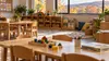 An empty early-childhood classroom with small tables, books and blocks in soft autumn light.