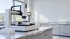 AI-generated editorial illustration of an empty generic laboratory with automated sample-handling equipment; not a photograph of Merck’s ADVANCE facility.