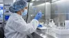 A compounding pharmacist inspects an unlabeled vial inside a sterile pharmacy laboratory.