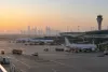 Ao amanhecer, os aviões de passageiros permanecem estacionados num pátio de aeroporto tranquilo, enquanto os veículos de emergência estão nas proximidades, ilustrando a interrupção no aeroporto internacional de Riade.