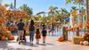 Families walking through a colorful Southern California amusement and splash park decorated for autumn