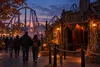 Anonymous visitors approach a generic haunted attraction at a Midwestern amusement park during a fall evening event.