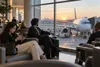Travelers wait in a modern airport terminal near a parked passenger aircraft