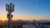 Mga cellular antenna at isang communications satellite sa itaas ng isang lungsod sa madaling araw, na naglalarawan ng isang hybrid wireless network