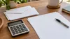 AI-generated illustration of blank financial-planning papers, envelopes and a calculator; not an actual ballot or tax document.