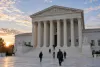 O edifício do Supremo Tribunal dos Estados Unidos ao nascer do sol, com pessoas a aproximarem-se dos seus degraus de mármore