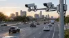 Automated traffic cameras mounted above a multi-lane city highway at sunrise