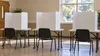 AI-generated editorial illustration of a quiet generic voting area with blank privacy booths; not an actual Tennessee polling place or documented voting event.