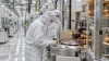 Semiconductor engineers inspect wafer-processing equipment inside a modern cleanroom.