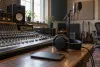 AI-generated illustrative photograph of headphones and an unbranded phone on a recording-studio console