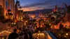 Guests descending into a Southern California movie-studio theme park illuminated for an autumn nighttime event