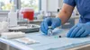 Public health nurse preparing an unlabeled vaccine vial and syringe at a clinic station