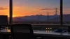 Editorial illustration of an unlabeled utility control desk and network cable with Utah desert power lines visible at dusk.