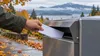 Editorial illustration of an anonymous voter placing a sealed ballot envelope into a generic drop box in an autumn Pacific Northwest setting.