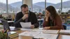 A school administrator and teacher review budget documents in a classroom overlooking Appalachian hills.