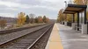 AI-generated illustrative view of railway tracks beside a simple empty platform in a Midwestern setting; not a photograph of a planned Hiawatha West station.