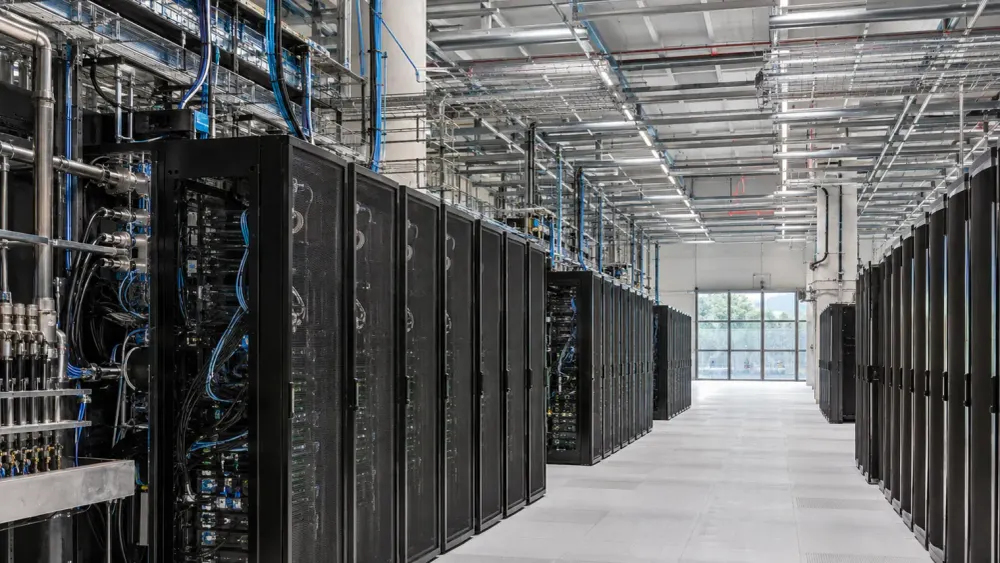 Filas de racks de servidores sin marca y refrigerados por líquido dentro de un moderno centro de computación de alto rendimiento