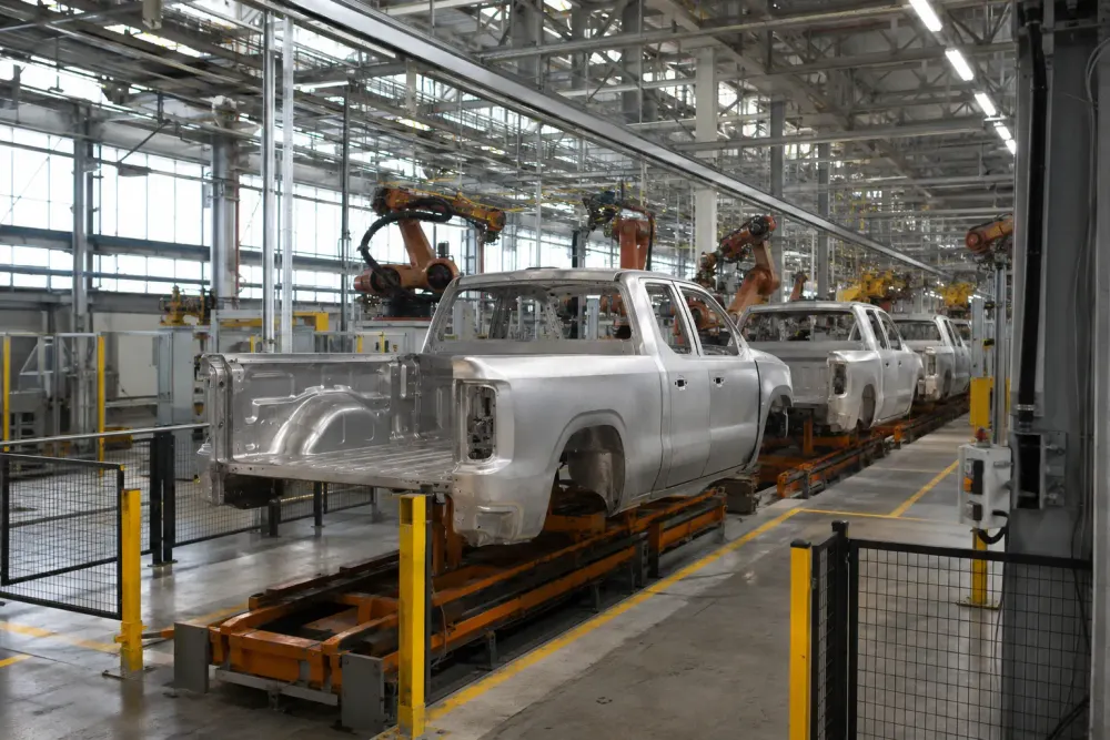 Unbranded pickup truck bodies moving through a modern automotive assembly plant