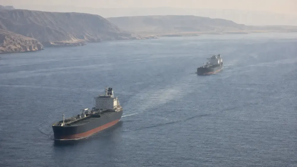 Two unbranded commercial tankers travel through the Strait of Hormuz in natural morning haze