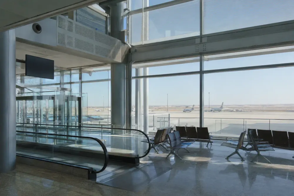 An empty modern airport transit concourse overlooking unbranded aircraft and an arid horizon