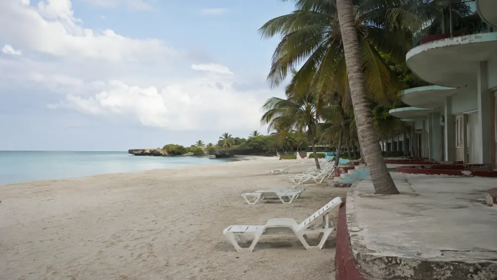 Empty lounge chairs beside a quiet Cuban beach resort in soft natural morning light