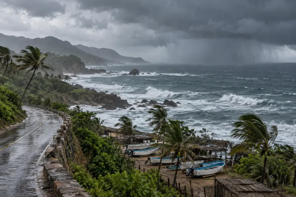 Storm clouds and rough Pacific surf approach a coastal road and secured fishing boats in Mexico.