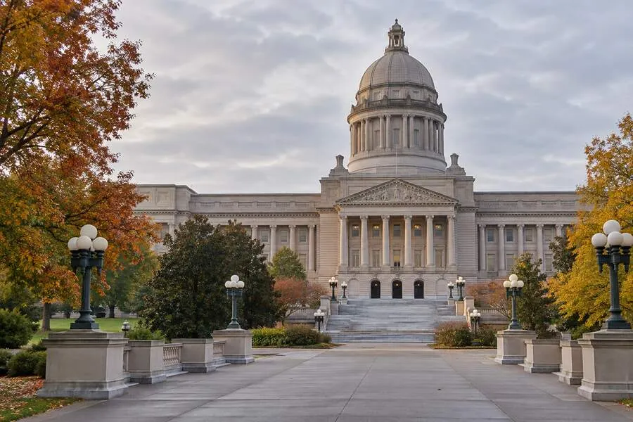 Kentucky State Capitol in Frankfort framed by autumn trees under an overcast sky