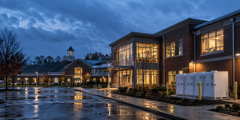 Battery storage cabinets outside a lit Massachusetts public building after a storm