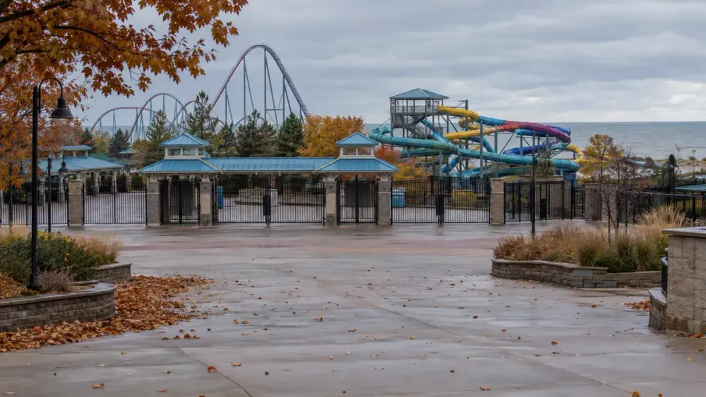 Closed amusement and water park entrance in Michigan during early autumn with roller coaster and water slides beyond the gates