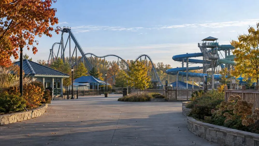 Empty amusement park midway with a roller coaster and water slides on a quiet autumn morning