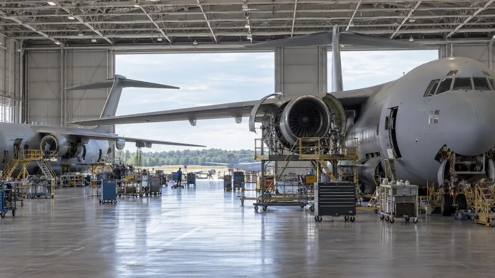 Generic military transport aircraft undergoing maintenance inside a large modern aviation hangar