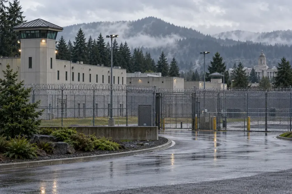 Illustrative view of a generic Oregon correctional facility behind perimeter fencing on a rainy morning