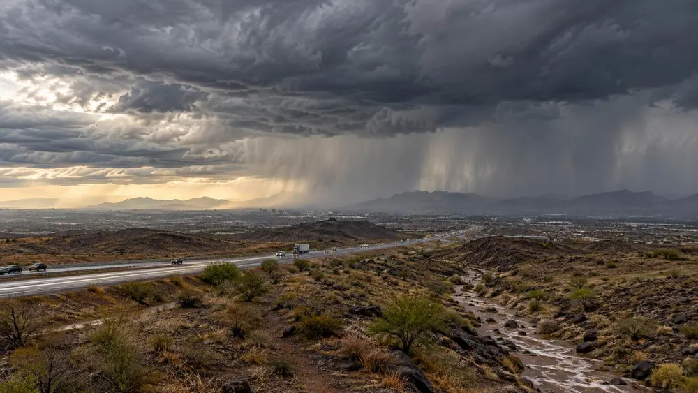 Heavy rain falls from a large storm over a desert city and interstate in the U.S. Southwest.