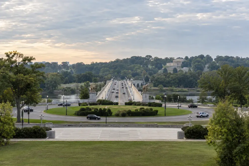 A landscaped traffic circle and stone bridge along the Washington memorial corridor in soft morning light