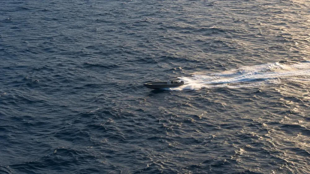 An unmarked high-speed boat crosses open water in a representative maritime-surveillance scene.