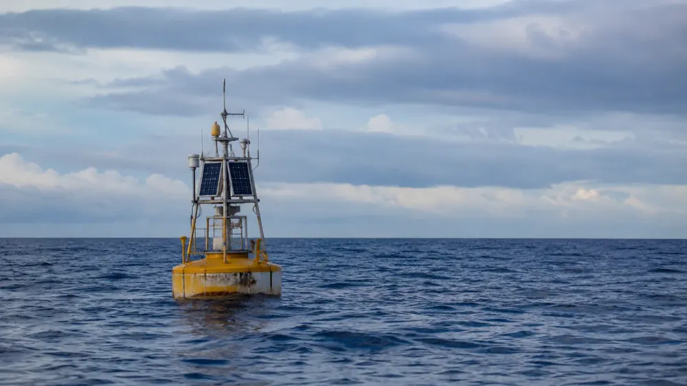 Una boya de monitoreo oceanográfico sin marca que flota en el Pacífico abierto bajo un cielo cubierto de nubes en capas