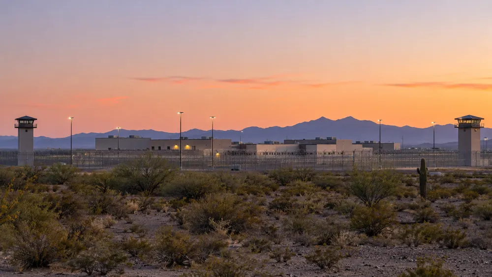 Illustrative distant view of a generic Arizona correctional complex beyond a sparse desert foreground.