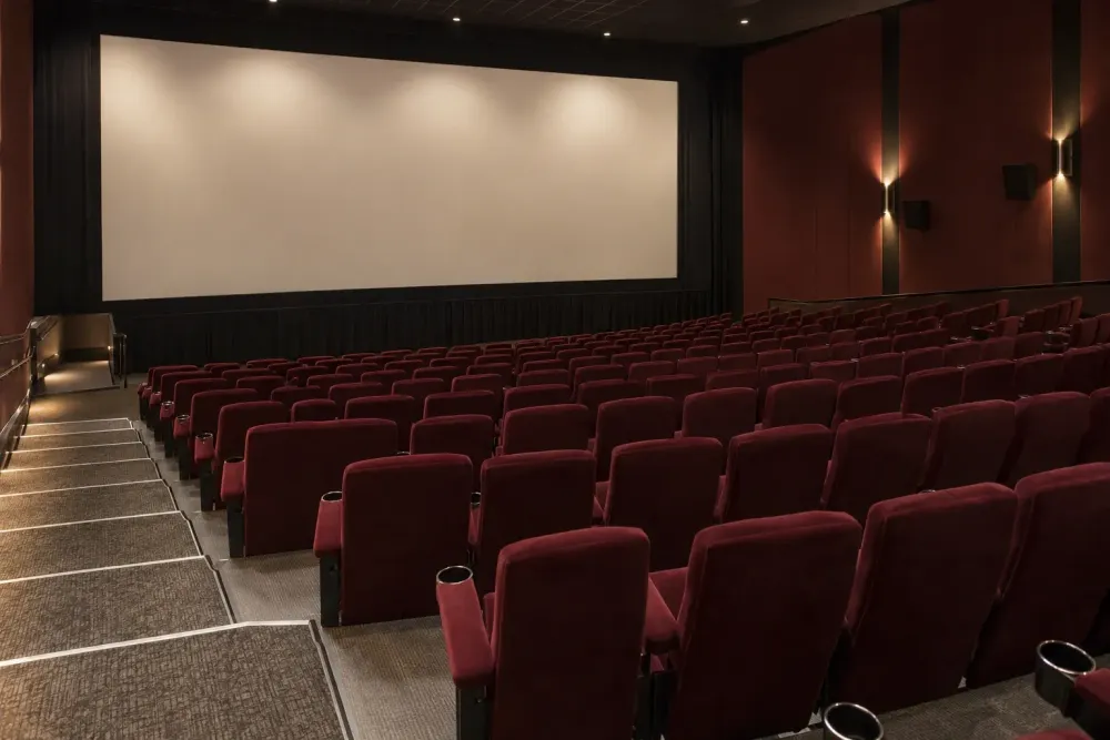 AI-generated illustrative view of an empty movie theater with burgundy seats and a blank screen.