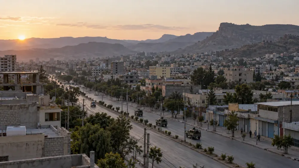 Uma vista panorâmica de uma cidade montanhosa da Etiópia ao amanhecer, com veículos militares ao longe numa estrada aberta