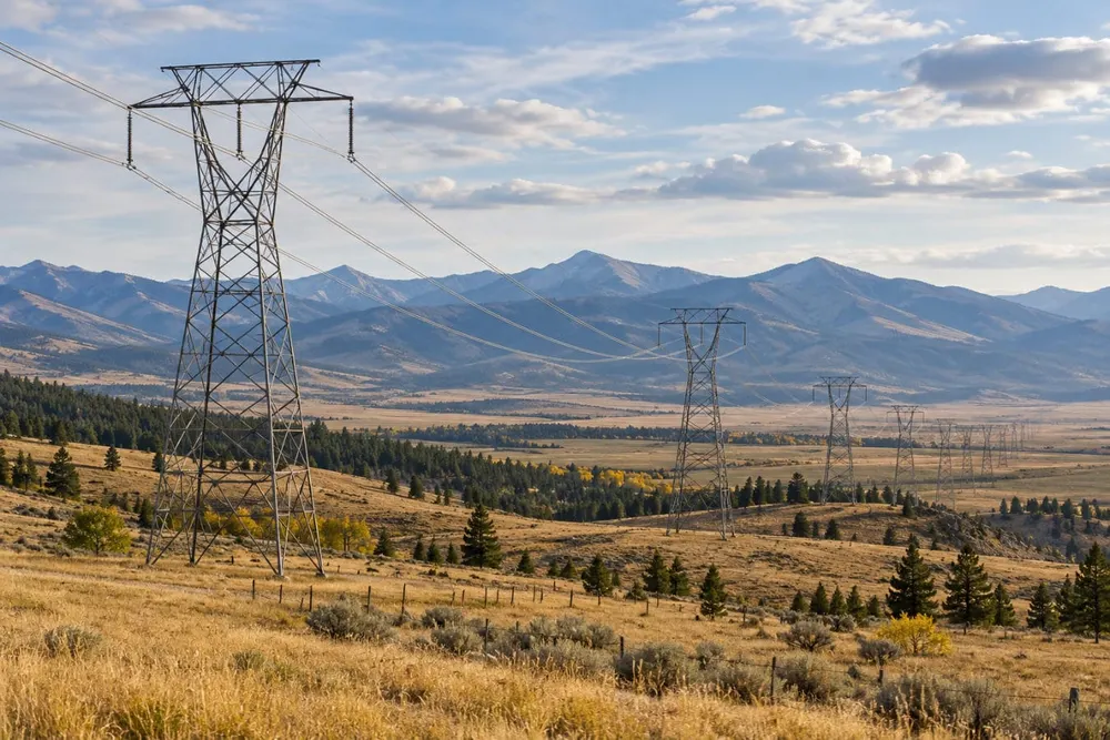 AI-generated illustration of electricity transmission lines crossing open Northern Rockies foothills; not a photograph of a named Montana utility, project or court event.