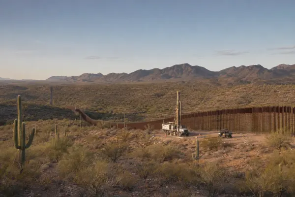 A soil-drilling truck beside steel border bollards in the Sonoran Desert of southern Arizona